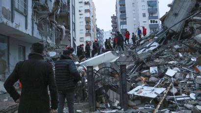 Bild: Uncredited/IHA/AP/dpa
Menschen und Rettungsteams versuchen, eingeschlossene Bewohner in eingestürzten Gebäuden zu erreichen.