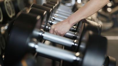 Bild: Oliver Berg/dpa/Symbolbild
Eine Frau nimmt in einem Fitnessstudio Hanteln aus dem Ständer.