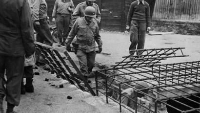 Archivbild: Holocaust Memorial Program, Oregon State University
Brigadegeneral Milton B. Halsey, Kommandeur der 97th Infantry Divison, steigt im April 1945 mit seinen Begleitern im von der US-Armee befreiten Konzentrationslager Flossenbürg den Gang zum Krematorium hinunter.