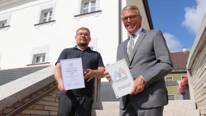 Bild: Stadt Tirschenreuth/exb
Projektleiter Falk Leopold von Brückner & Brückner Architekten (links) und Bürgermeister Franz Stahl (rechts) mit der Auszeichnungsplakette und Urkunde vor dem neuen Lernstandort.