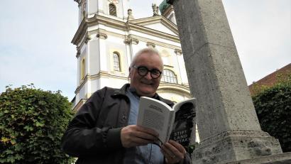 Bild: ubb
Die kleine Passage, die Autor Thomas Bäumler am Brunnen vor der imposanten Basilika in Waldassen vorliest, klingt vielversprechend. Bäumler sagt, neben den Morden geht es auch lustig zu in seinem Buch. Spannung pur mit Unterhaltung also.