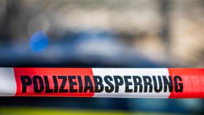 Bild: David Inderlied/dpa/Illustration
Ein Absperrband mit der Aufschrift „Polizeiabsperrung“ ist vor einem Polizeiwagen aufgespannt.