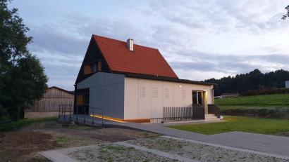 Bild: öt
Im Abendlicht präsentiert sich das generalsanierte Kolpinghaus mit indirekt beleuchtetem, barrierefreiem Zugang. Das ursprüngliche Gebäude zeigt sich nun in den Kolpingfarben schwarz und orange. Der frühere Anbau ist mit grauen Platten verkleidet.
