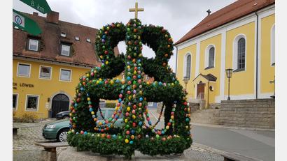 Bild: gi
Die Osterkrone mit ausgeblasenen und handbemalten Hühnereiern auf dem Brunnen am Marktplatz ist wieder ein Schmuckstück. Frauen des Katholischen Frauenbundes haben ihn geflochten und geschmückt.