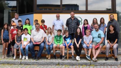Bild: Stadt Schönsee/exb
Sieben Bänke werten in der Grundschule die Pausenbereiche im Freien auf. Rektor Troidl, die Sponsoren und die Kinder der vierten Klasse nutzten die Gelegenheit für ein Probesitzen.