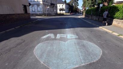 Bild: Martin Schutt/dpa
Ein blaues Herz und der Schriftzug AfD sind mit Kreide auf eine Straße in Sonneberg gemalt.