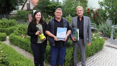 Bild: Stadt Tirschenreuth/exb
Dritter Bürgermeister Norbert Schuller (rechts) und die Leiterin der Tourist-Info, Birgit Plößner (links), überreichten Jörg Wolf zum Urlaubs-Jubiläum neben einer Urkunde auch die aktuelle Chronik der Stadt Tirschenreuth und eine Flasche Wein.