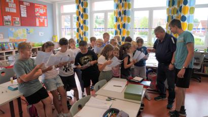 Bild: fvo
Bürgermeister Hans-Peter Reil und Marktverwaltungs-Praktikant Johannes Reber (rechts) übergeben den druckfrischen Kinderferienprogramm-Flyer an die Mädchen und Buben der Wolfgang-Caspar-Printz-Grundschule, die ihn gleich interessiert studieren.