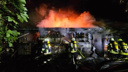 Bild: Feuerwehr Eschenbach 
Feuerwehrleute löschen das brennende Bootshaus am Rußweiher.
