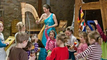 Bild: Wurzer Sommerkonzerte
Harfenistin Silke Aichhorn musiziert zusammen mit Kindern.