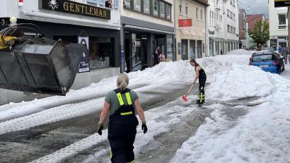 Bild: Schulz/SDMG/dpa
Einsatzkräfte der Feuerwehr räumen Hagel von einer Straße in Reutlingen.