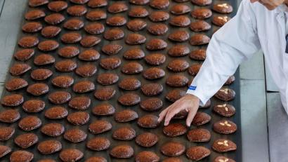 Bild: Daniel Karmann/dpa
Frisch gebackene Lebkuchen laufen auf einem Band aus einem Ofen.