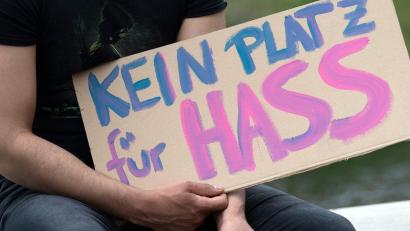Bild: Paul Zinken/dpa/Symbolbild
„Kein Platz für Hass“ steht auf dem Plakat eines Demonstranten auf einem Pappschild.