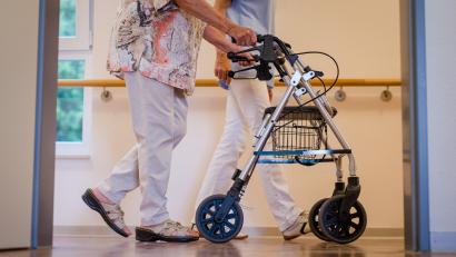 Symbolbild: Christoph Schmidt/dpa
Eine Pflegekraft begleitet eine Seniorin mit dem Rollator. Wie wollen Politiker den Spagat zwischen fairem Lohn und steigenden Heimkosten schaffen?