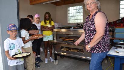Bild: gi
Maria Bayer-Schmidt (rechts)vom Frauenbund Moosbach zeigt den Kindern welche Kräuter essbar sind und auf der Pizza lecker schmecken.