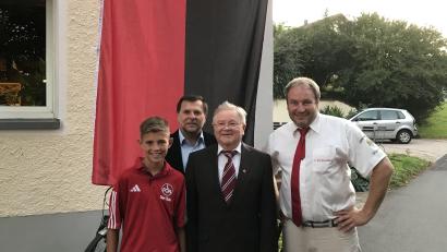 Bild: FCN-Fanclub Zur Linde Kleinfalz/exb
Erinnerungsfoto vor der rot-schwarzen Fahne: Club-Jugendspieler Lukas Kellner, Zweiter Bürgermeister Günther Koller, der für 25 Jahre Mitgliedschaft geehrte Altbürgermeister Gerd Geismann und Präsident Mike Schulz.