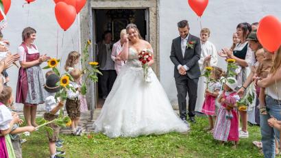 Bild: do
Die Kleinkindgruppe des Kindergartens Pleystein empfängt das Brautpaar Céline Plohmann und Mario Sauer nach der kirchlichen Trauung in der Wallfahrtskirche St. Ulrich bei Pleystein in schicker Tracht mit Sonnenblumen und roten Herzballons.