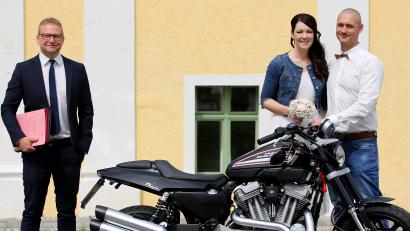 Bild: exb
Stefanie Kett und Stephan Bösl sind nun ein glückliches Ehepaar. Standesbeamter Stefan Bäuml (links) freut sich, dass das junge Paar ihren Traum vom eigenen Hochzeitsfahrzeug, einem Motorrad, bewahren konnte.