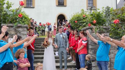 Bild: Wolfgang Steinbacher
Veronika und Jürgen Leißner auf dem Weg durch ein langes Hochzeitsspalier vor der Kirche Corpus Christi in Eschenfelden.