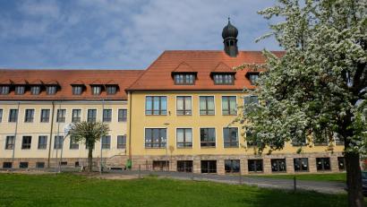 Bild: do
Geplant ist die OGS auf dem Wiesengrundstück (im Vordergrund) gegenüber dem Gebäudekomplex der Grund- und Mittelschule.