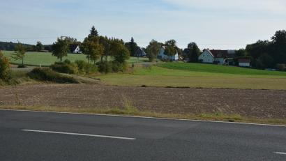 Bild: jr
Hier an der Straße zwischen Konnersreuth und Waldsassen soll eine der zwei nahe Neudorf (hinten) geplanten Freiflächen-Photovoltaikanlagen entstehen. Nach aktuellem Stand würde der Abstand zur Wohnbebauung nur knapp 100 Meter betragen.