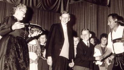 Archivbild: Sepp Strobl
Mit den Liedern „He Michl“ und dem Schnodahüpfl „Dou hint san ma vira“ gewannen die „Hirschauer Boum“ Heiner Schuster (Mitte links) und Werner Schulz (Mitte rechts) am 13. Oktober 1963 den ersten Preis beim 3. Bayerischen Kinder- und Jugendsingen. Als Siegerpreis überreichte Annette Thoma (links) eine Zither. Außerdem gratulierte Radio- und Fernsehmoderator Wastl Fanderl (rechts).