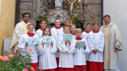 Bild: soj/exb
Pfarrer Pater Anish George (links) und Diakon Rudi Hoffmann (rechts) mit den neuen Ministranten nach dem Aufnahmegottesdienst an der Grotte auf dem Kirchplatz.