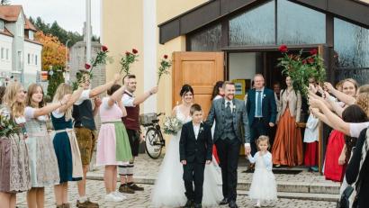 Bild: Maria Schlögl/exb
Das Hochzeitspaar Marina Frimberger und Tobias Lang durchschreitet in Wernberg-Köblitz ein Rosenspalier.