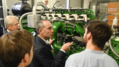 Bild: gf
Max Becker, Wissenschaftlicher Mitarbeiter im Kompetenzzentrum der OTH (rechts) erklärt Bayerns Vizeministerpräsident Hubert Aiwanger (vor der Anlage) das neue Wasserstoff-Blockheizkraftwerk am Campus. Mit dabei waren auch Clemens Bulitta, Präsident der OTH Amberg-Weiden (links) und Professor Raphael Lechner.