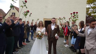 Bild: bk
Lukas Bäumler und Rebecca Luber schreiten nach ihrer Hochzeit durch das Rosenspalier ins Eheglück.