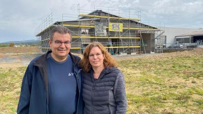 Bild: ck
Martin und Cornelia Busch vor dem Neubau, in dem der Prüfingenieur ab Sommer 2024 Fahrzeuge wie Autos, Lkw, Busse und Nutzfahrzeuge prüfen wird. Wie beim Tüv oder den anderen Prüforganisationen kann man hier künftig eine Plakette für die Hauptuntersuchung oder Sicherheitsprüfung erhalten. Der Altentreswitzer wird mit seinem kleinen Team weiterhin auch im Außendienst unterwegs sein.