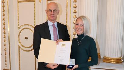 Bild: Regierung der Oberpfalz/Stühlinger-Weinhändler/exb
Regierungspräsident Walter Jonas ehrt Christina Brumer aus dem Schwandorfer Ortsteil Bubach für die Erstversorgung eines verletzten Motorradfahrers. Sie erhält dafür eine öffentliche Anerkennungsurkunde mit Medaille.