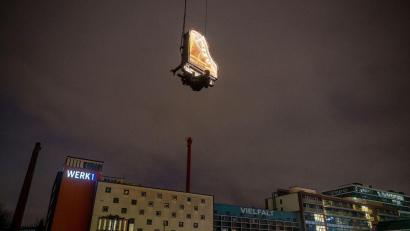 Bild: Peter Kneffel/dpa
Der Künstler Alain Roche sitzt an seinem beleuchteten Flügel, der an einem Kran gehalten wird.