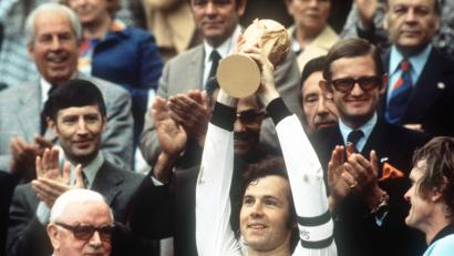Bild: Hartmut Reeh/ picture alliance / dpa
Kapitän Franz Beckenbauer (Mitte) hebt an der Seite von Torhüter Sepp Maier (rechts) und dem englischen FIFA-Präsidenten Stanley Rous (links) am 7. Juli 1974 nach dem Finalsieg gegen die Niederlande (2:1) im Münchner Olympiastadion den eroberten WM-Pokal hoch. Der "Kaiser" hat dem Verein Fanhilfe ein ähnliches Bild zur Versteigerung signiert zur Verfügung gestellt.