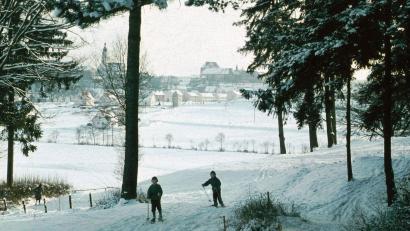 Bild: Archiv Ostermann
Zwei Kinder auf Skiern in einer Winterlandschaft vor prächtiger Sulzbach-Rosenberger Stadtkulisse: Ende der 1950er, Anfang der 1960er Jahre war Wintersport auch im Bereich des heutigen Stadtteils Erlheim öfters möglich.