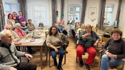 Bild: BRK Kreisverband Tirschenreuth/exb
Michaela Domeyer mit Habichtskauz-Dame Birke in Mitten aller Gäste und Mitarbeiterinnen der BRK-Tagespflege d’Stawoldstubn Erbendorf.