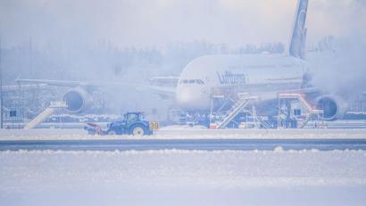 Bild: Jason Tschepljakow/dpa
Ein Schneeräumer fährt im Schneetreiben auf dem Flughafen vor einer Maschine entlang.