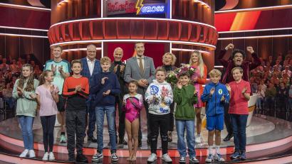 Bild: © NDR/Thorsten Jander, 
Der zwölfjährige Markus Stauber aus Vohenstrauß (vorne, Vierter von rechts) blieb cool und gewann gegen Herausforderer und Schauspieler Jan Josef Liefers. Er flippte 16 aufgebaute 1,5 Liter Flaschen in die Baggerschaufel. Liefers schaffte 14 Flaschen. Seine Heimat hat er in der Bundeshauptstadt bestens vertreten.
