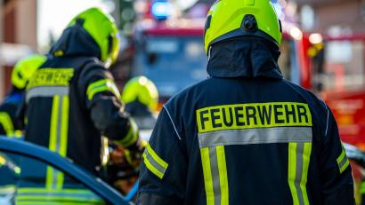 Bild: David Inderlied/dpa/Symbolbild
Feuerwehrleute stehen um ein Auto, das einen Unfall gehabt hat.