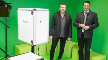 Bild: Hirsch
Der Leiter des Medienzentrums Schwandorf, Alexander Friedl (links), erklärt Landrat Thomas Ebeling (rechts) die Funktion der Fotobox. Der neutrale grüne Anstrich der Wände eignet sich besonders gut für eine thematische Hintergrundgestaltung, wie man sie von den Nachrichtensendungen im Fernsehen her kennt. .