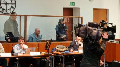 Bild: scm
Der Angeklagte sitzt, wie die Verhandlungstage zuvor, mit gesenktem Kopf auf der Anklagebank hinter einer dicken Glasscheibe.