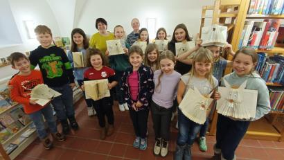 Bild: wku
Stolz zeigen die Kinder die Ergebnisse des Buchfalt-Workshops. Hinten Büchereileiterin Maria Klobes-Martin (rechts) und die Expertin Christine Simmel (links).