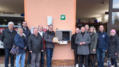 Bild: gis
Am Unterlinder Feuerwehrhaus wurde ein "Defi" installiert. Darüber freuen sich Bürgermeister Franz Tauber (Sechster von links) und Karl Bernet (Fünfter von links) sowie Vertreterinnen und Vertreter der Gemeinde und der Sponsoren.