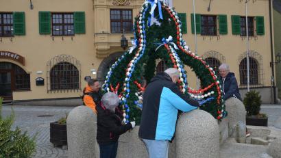 Bild: dob
Mit vereinten Kräften hieven die Siedlergemeinschaftsmitglieder die grüne Krone mit den Eiern in Stadtfarben auf den Granitbrunnen. Alexander Thomas, Margit Kreisl, Josef Dobmayer und Renate Wührl (von links nach rechts) packen kräftig mit an.