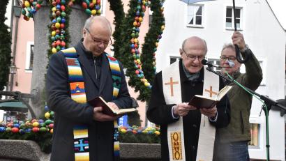 Bild: hcz
Dekan Thomas Guba und Pfarrer Andreas Uschold segnen den Osterbrunnen. Als "Schirmherr" wirkte wegen des andauernden Regens Bürgermeister Reinhold Wildenauer.