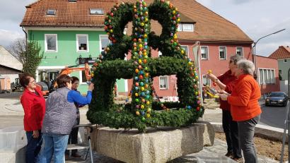 Bild: gi
Die Osterkrone mit ausgeblasenen und handbemalten Hühnereiern auf dem Brunnen am Marktplatz in Moosbach ist wieder ein Schmuckstück, das der Frauenbund gestaltet hat.