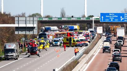 Bild: Jan Woitas/dpa
Einsatzfahrzeuge und Rettungshubschrauber stehen auf der A9 an der Unfallstelle.