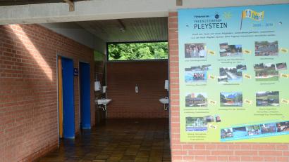 Bild: bey
Der Zugang zu den Sanitärräumen ist wie Toilettenanlagen sanierungsbedürftig. Die Bildtafel (rechts) zeigt, dass sich der Freibadförderverein seit 2004 um das Freibad und dessen Erhalt bemüht.