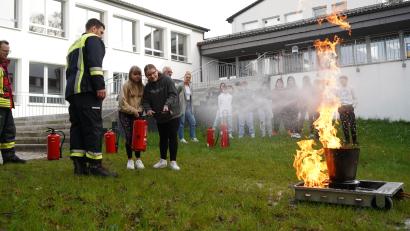 Bild: kaz
30 Feuerwehrleute aus 13 Feuerwehren präsentieren sich und ihr Ehrenamt beim Feuerwehrtag an der Mittelschule Ebnath. Edyta Kaczmarczyk und Katharina Heimerl (von links) probieren einen Feuerlöscher aus. Infos gibt Julian Heinl, Kommandant bei der Feuerwehr Schwarzenreuth.