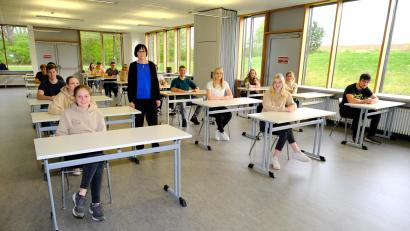 Bild: Stiftland-Gymnasium/exb
Das Foto zeigt einige Abiturientinnen und Abiturienten im Prüfungsraum mit ihrer Oberstufenkoordinatorin Tanja Bachfischer.